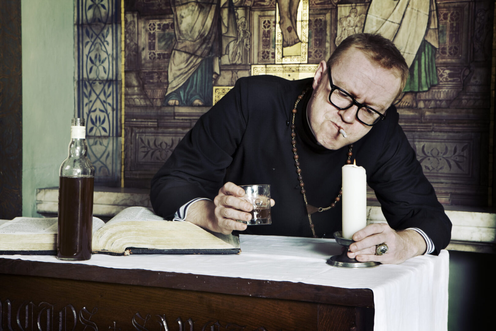 A man sitting at a table with a candle and glass of wine.