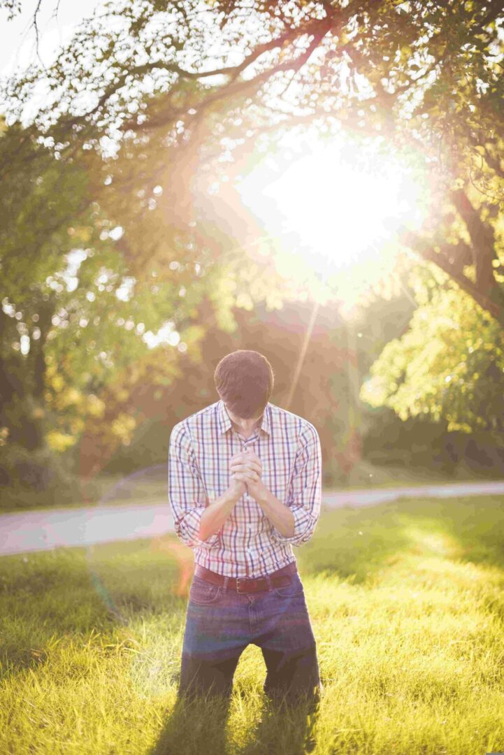 A man standing in the grass with his hands clasped.